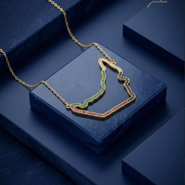 18K gold UAE map necklace with ruby and emerald stones on dark luxury background
