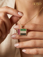 Gold necklace with a colorful pendant worn by a person, with 'ROKO' branding.