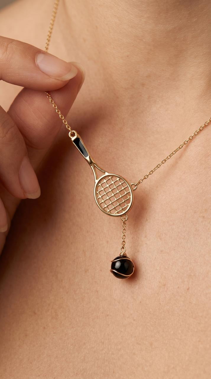 Gold necklace with tennis racket pendant and black bead on a person's neck