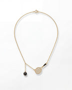 Gold necklace with a tennis racket and ball pendant on a white background